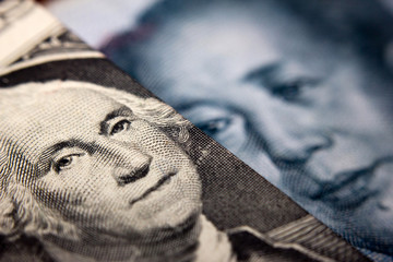 Close-up of an American dollar bill (showing George Washington) and a Chinese yuan banknote (Mao Zedong)