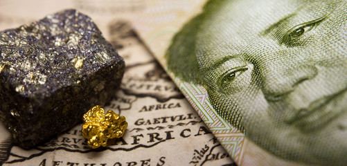 Close-up of a 1 yuan Chinese banknote (figuring Mao) and a gold nugget / rare earth metal on top of...