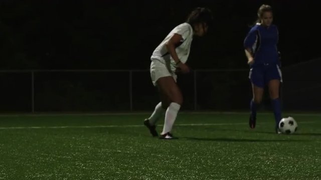 A female soccer player being defended by her opponent