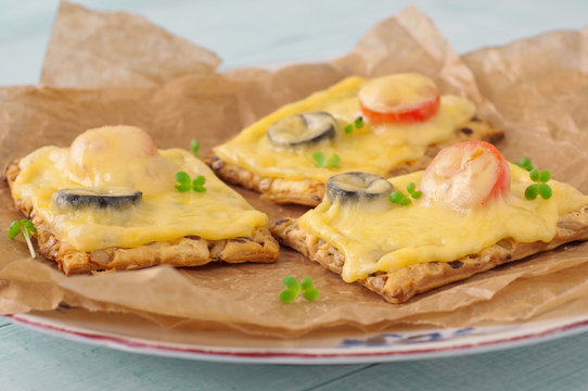 Closeup canapes with melted cheese, cherry tomatoes and olives