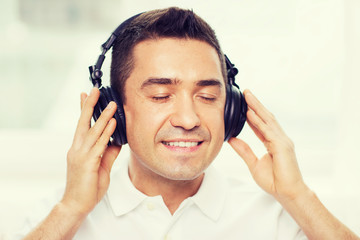 happy man in headphones listening to music at home
