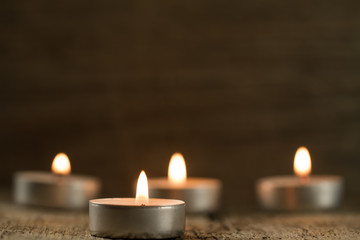  light  burning brightly candles on old wooden background. Spa, meditation, ritual, flavored.