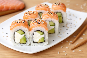 Sushi roll with feta cheese, avocado, cucumber, salmon and sesame seeds