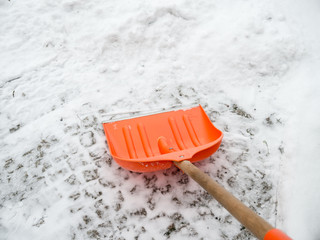 Snow removal. Orange Shovel in snow, ready for snow removal, outdoors.