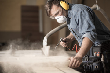 Professionally dressed carpenter varnishing board