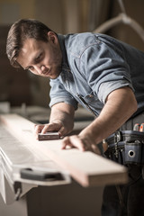 Handsome carpentry employee grinding board