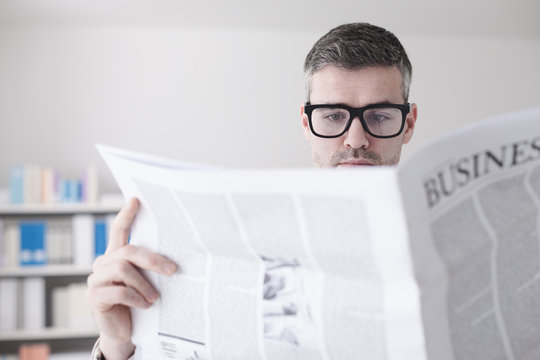 Confident businessman reading a newspaper