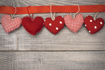 Textile hearts hung on red ribbon.