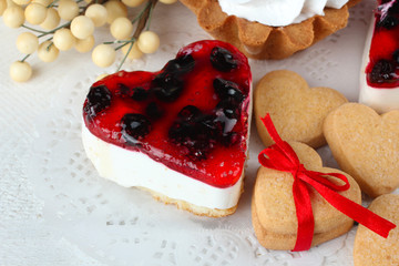 cake with jam and cookies in the shape of heart with bow on wooden table