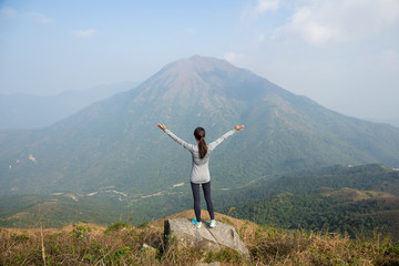 Woman standing at the peak and raising up her hand