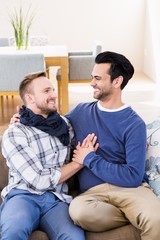 Fototapeta premium Gay couple looking at each other on the couch