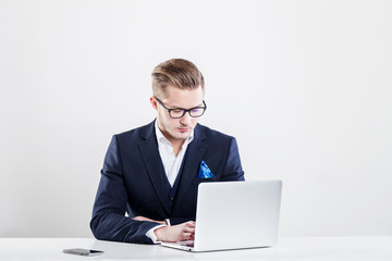 Young businessman working in office, sitting at desk, looking at laptop computer