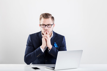 Young businessman working in office, sitting at desk, looking at laptop computer