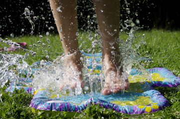 girl jumping into sprinkler