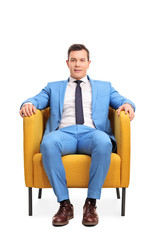 Man in a blue suit sitting in an armchair