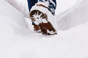 Man walks through the deep snow in a winter day.