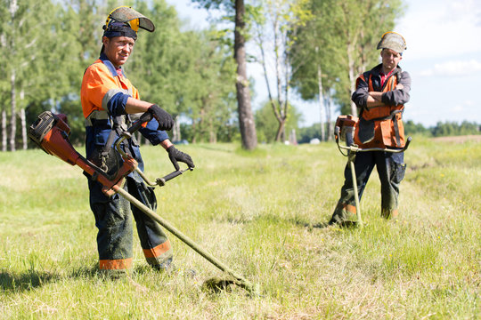 Positive landscapers men workers with gas handheld string trimmers