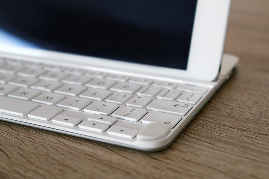 Detail of white tablet with keyboard at office