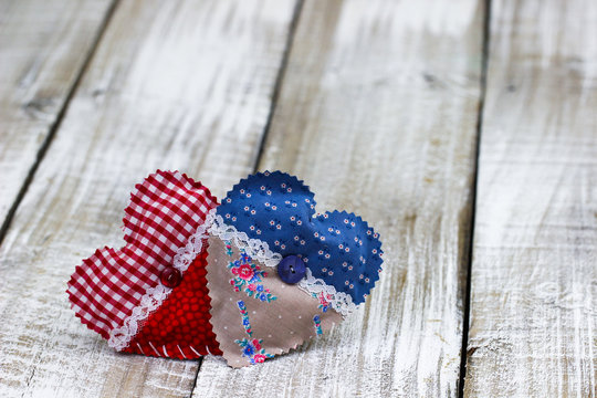 Red and blue fabric hearts on antique white wood background