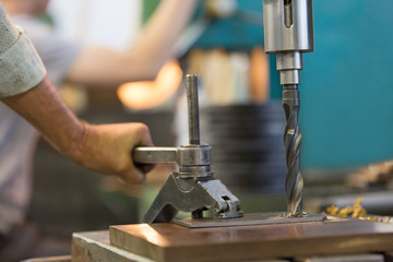 Drilling hole in metal sheet with auger during man worker fixing workpiece