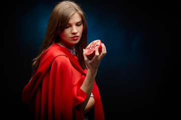 beautiful woman with red cloak holding pomegranate