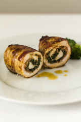 Roulade of turkey with chorizo and spinach. On white plate and white background.