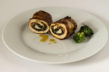 Roulade of turkey with chorizo and spinach. On white plate and white background.