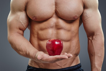 man holding a fresh red apple on grey background.