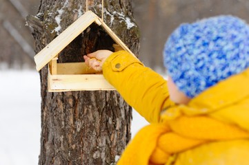 Beautiful girl feeding birds in winter.