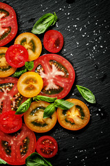 Ingredients for the salad of colorful tomatoes and basil on a da
