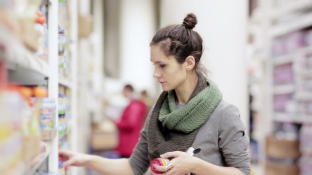 Young woman chooses baby food in the supermarket