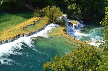 Naklejka na ściany i meble Green river and waterfall cascade surrounded by green trees