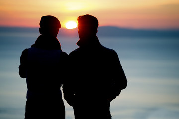 Silhouette of men watching sunset 