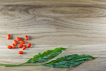 Herbal pills and tablets on a wooden background in a green bowl. Medicine