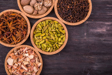 Специи в круглых формах на темной деревянной доске