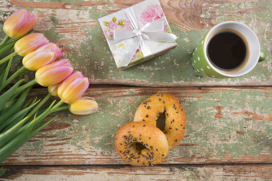 High angle view of breakfast, cup of coffee and bouquet of tulips on wooden table