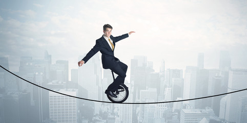 Brave guy riding a monocycle on a rope above cityscape © ra2 studio