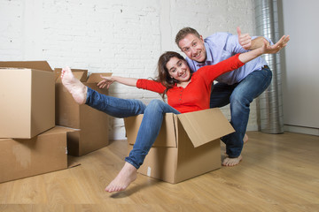 happy American couple unpacking moving in new house playing with cardboard boxes enjoying the apartment in real state concept