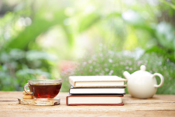 tea in glass and notebook with white teapot on wooden table at outside