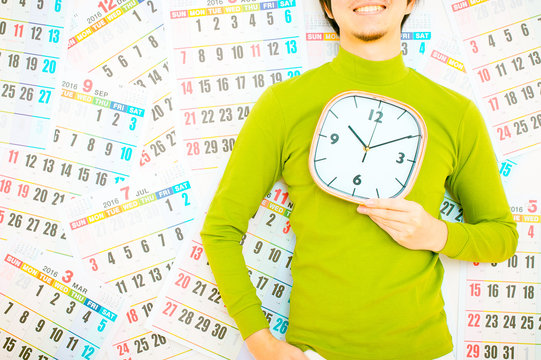 大きな掛け時計を男性持っている男性,緑の服