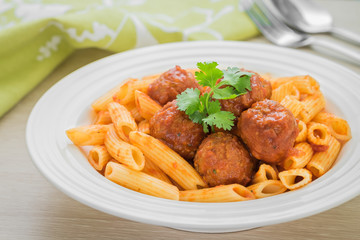 Penne pasta with meatballs in tomato sauce on plate