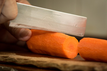 Chef peeling carrot with Knife.