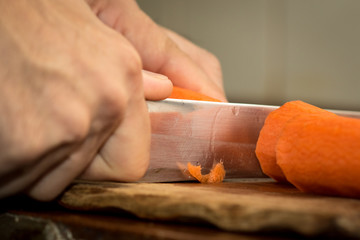 Chef peeling carrot with Knife.