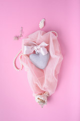 Saint Valentine’s day pink background with heart, silk ribbon and shells on a veil. 
Romantic greeting card, invitation design top view.
