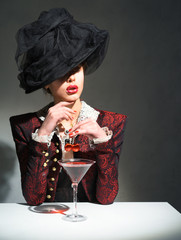 A woman in a vintage hat drinking a martini with a cherry