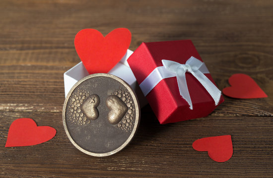 Valentines day card, red hearts in a gift box and chocolate with hearts on wooden background