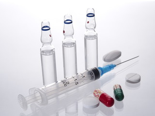 Medical vials for injection syringe and bright tablets, capsules on a white background 