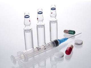 Medical vials for injection syringe and bright tablets, capsules on a white background 