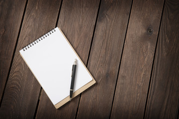 notebook with a pen on a wooden background