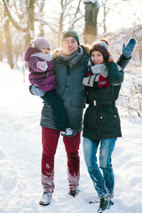 Couple with her daughter in winter forest